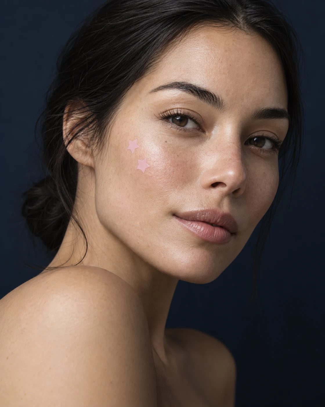 Beauty portrait with two small pink star patches on the cheek